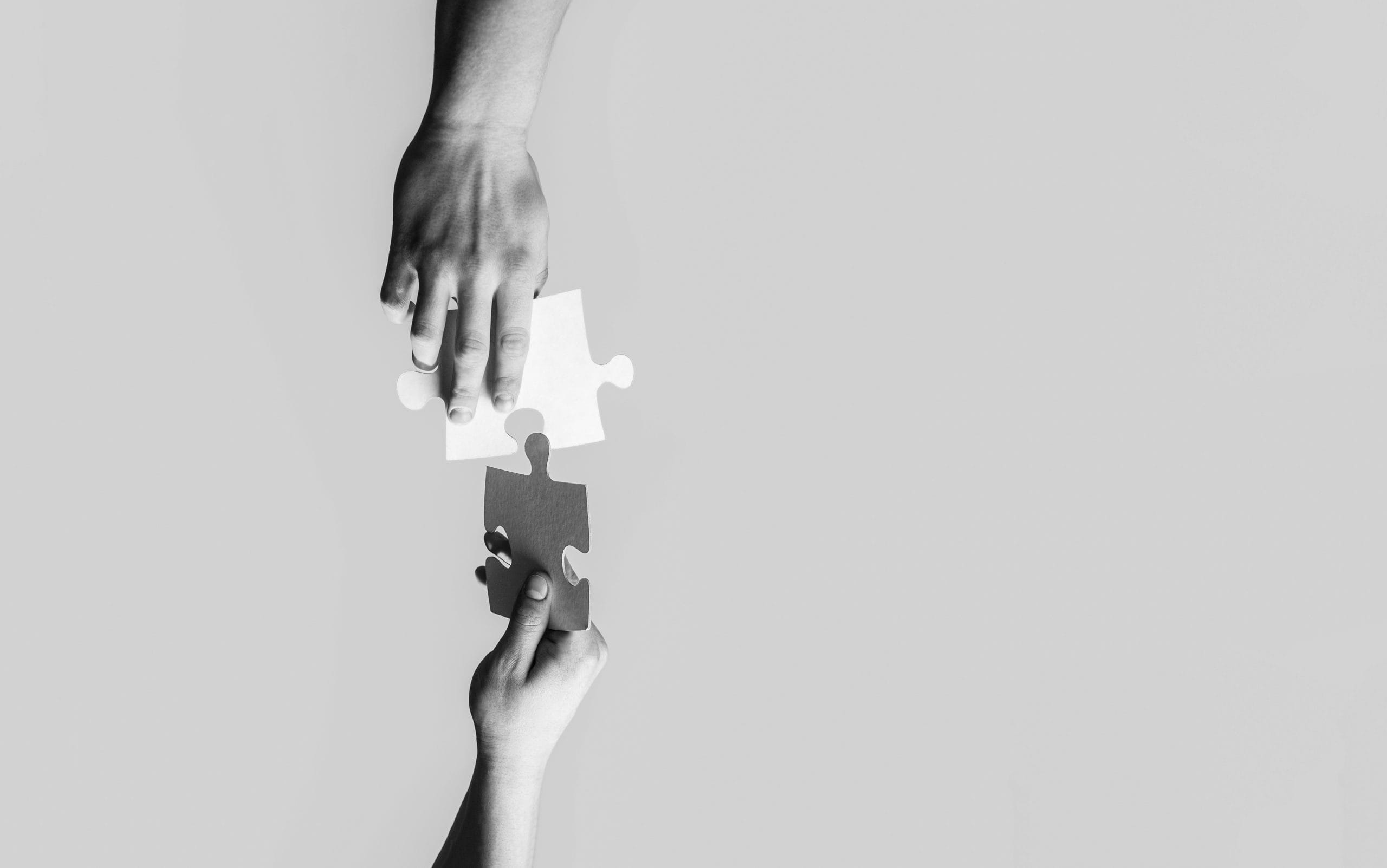 Closeup hands of man connecting jigsaw puzzle. Business solutions, success and strategy concept. Black and white. Two hands trying to connect couple puzzle with yellow background